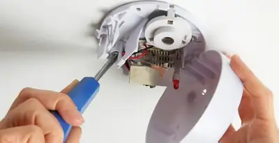 Certified technician wiring smoke detector during installation in San Francisco, CA